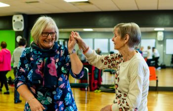 Two older women dancing together and smiling