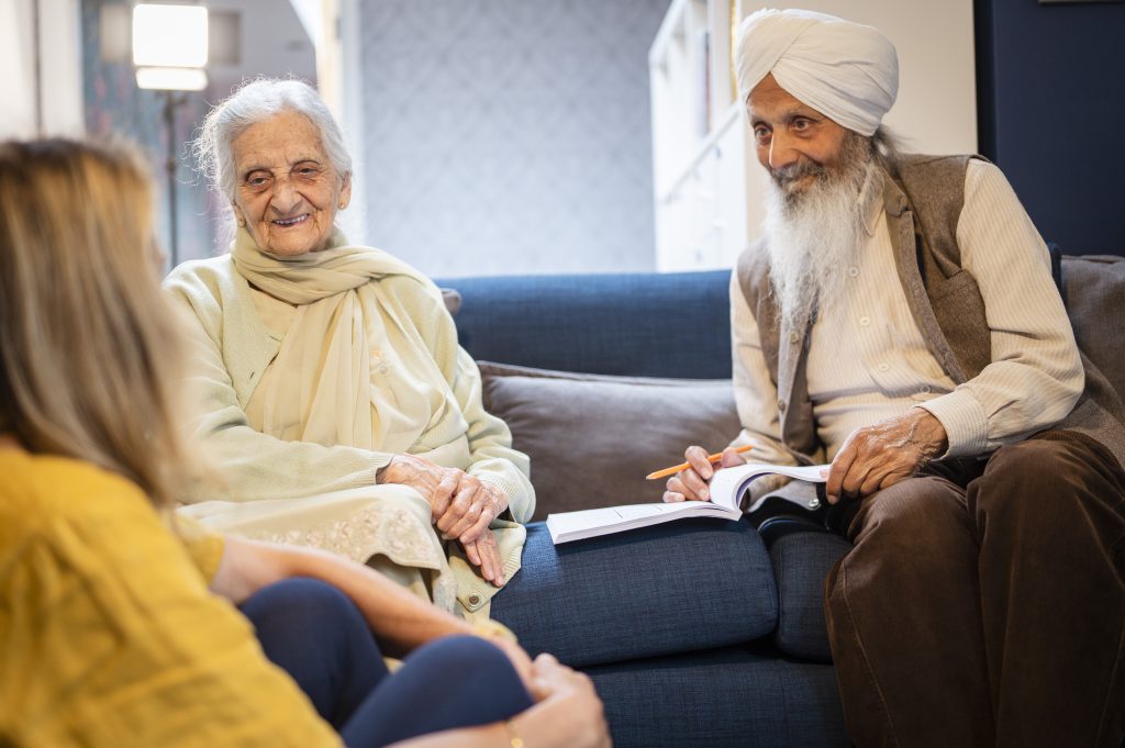 Older Sikh couple talking to a younger woman in their home