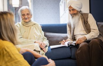 Older Sikh couple talking to a younger woman in their home